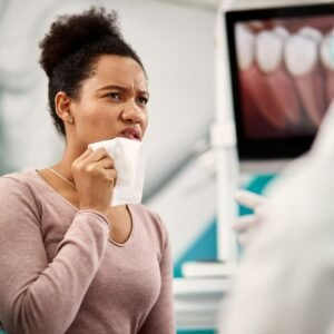 Displeased black woman with toothache talking to a dentist during appointment at dental clinic.